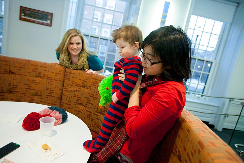 Resident Tutor Marie Dach (from left) watches her 1-year-old, Owen, being entertained by Yi-Jou Chiang during “PfoHo Fridays,” a weekly tradition in the Junior Common Room at Pforzheimer House on Radcliffe Quad. Rose Lincoln/Harvard Staff Photographer