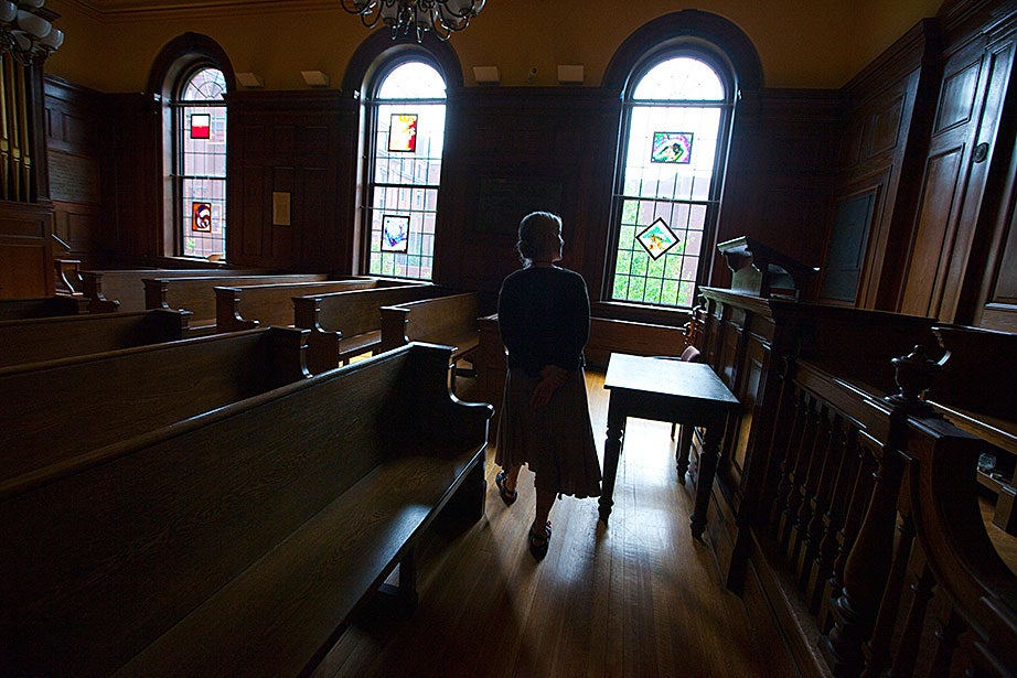 Staff assistant Bronwen Murphy walks through the Emerson Room as it looked in 2011. The benches have been taken out and now line the hallways of Divinity Hall; chairs, more easily moved, now occupy the space.