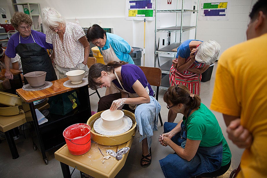 Ceramics instructor Monica Ripley (center) demonstrates throwing techniques with porcelain clay.