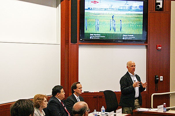 Harvard Professor William C. Clark (standing), an environmental scientist who moderated the panel, introduced 
Leslie Carothers (from left), former president of the Environmental Law Institute; Neil C. Hawkins, Dow’s vice president for sustainability and environment, health, and safety; and Glenn T. Prickett, external affairs officer for the Nature Conservancy.