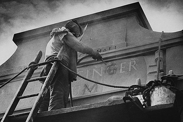 This 1958 photo shows a worker at Adolphus Busch Hall on Kirkland Street changing the name of Harvard's Germanic Museum to the Busch-Reisinger Museum — an outward sign of the museum's shifting identities in the 20th century. On paper, the official name change came in 1950.