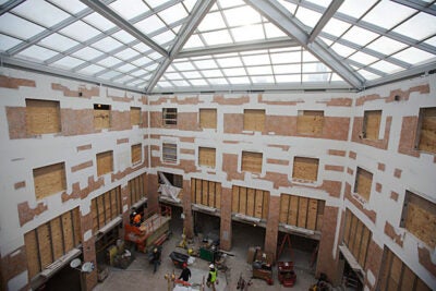 Workers renovate the Inn at Harvard as part of the House renewal and swing space projects (photos 1, 2). An artist's rendering shows what the atrium will look like upon completion (image 3).