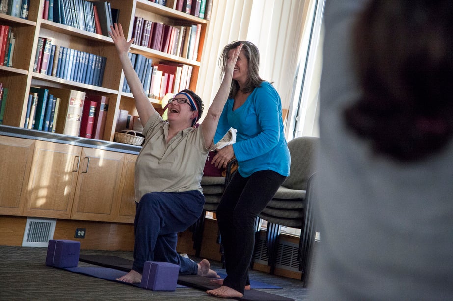 Instructor Marianne Bergonzi guides Harvard employee Colleen Bryant into a pose.