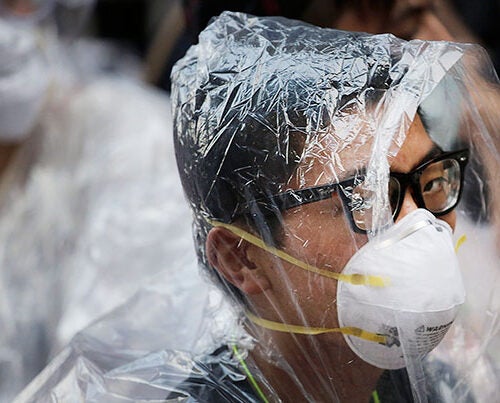 A student pro-democracy protester covers his face in plastic wrap to guard against pepper spray in a standoff with police in Hong Kong on Monday. Protesters expanded their rallies throughout Hong Kong, defying calls to disperse in a major pushback against Beijing's decision to limit democratic reforms in the Asian financial hub.
