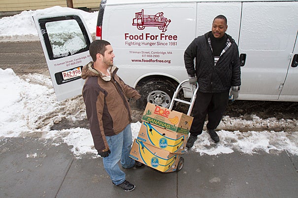 Director of programs at the Cambridge Community Center Darrin Korte (left) and Adam Collins wheel cartons of food from the Food for Free van into the center, which is one of the local organizations receiving donations from Harvard. 