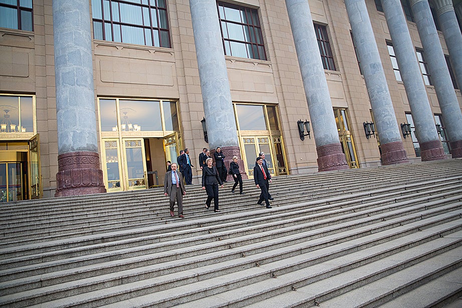 Drew Faust descends the stairs of the Great Hall of the People with Harvard delegation members.