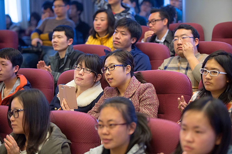 Tsinghua University students share a moment while using smart phones to record Drew Faust’s lecture. 