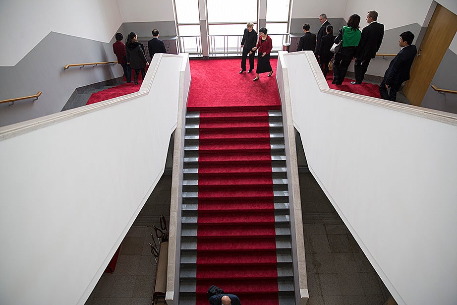 Chen Xu (right) and Drew Faust walk down a grand staircase at Tsinghua University.