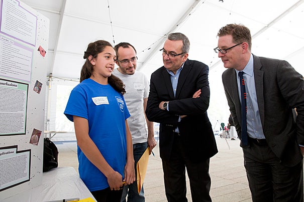 Eighth-grader Penelope Hernandez explains her science project to Harvard's Nicolas Full (from left), City of Cambridge Mayor David P. Maher, and Paul Andrew, vice president for Harvard Public Affairs and Communications, at the fifth annual Cambridge Public Schools Student Science and Engineering Showcase at Harvard.