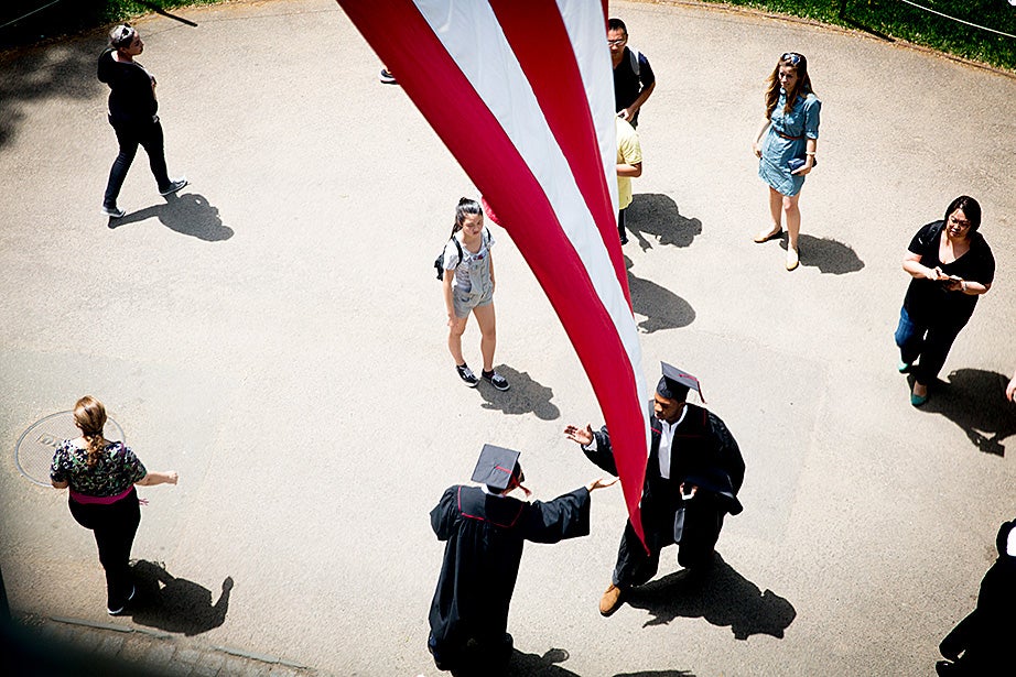 Students greet each other under the flag at University Hall prior to the Baccalaureate Service held each year inside the Memorial Church. Rose Lincoln/Harvard Staff Photographer