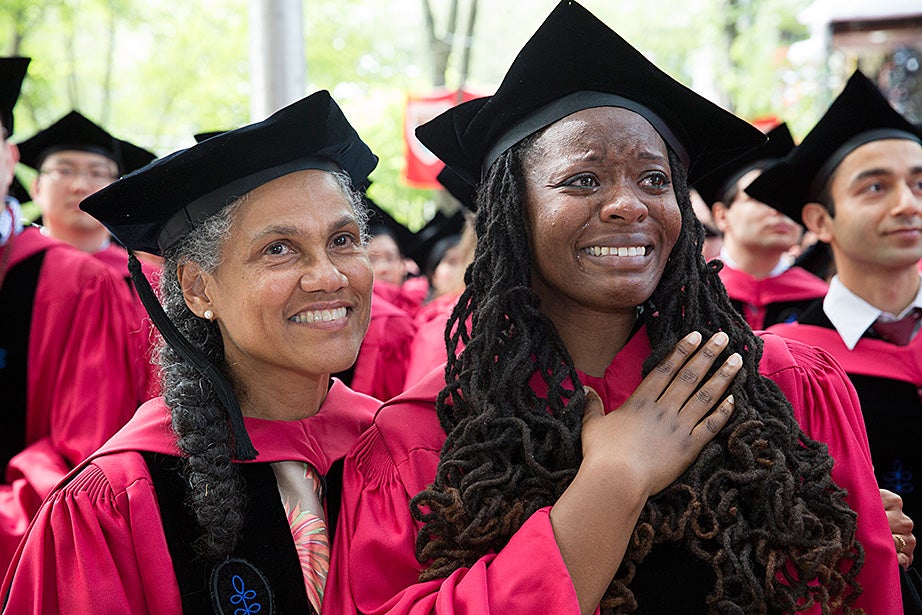 Jovonne Bickerstaff sheds some tears as she and Jacqueline Rivers rise for the Graduate School of Arts and Sciences’ conferral of degrees. Jon Chase/Harvard Staff Photographer