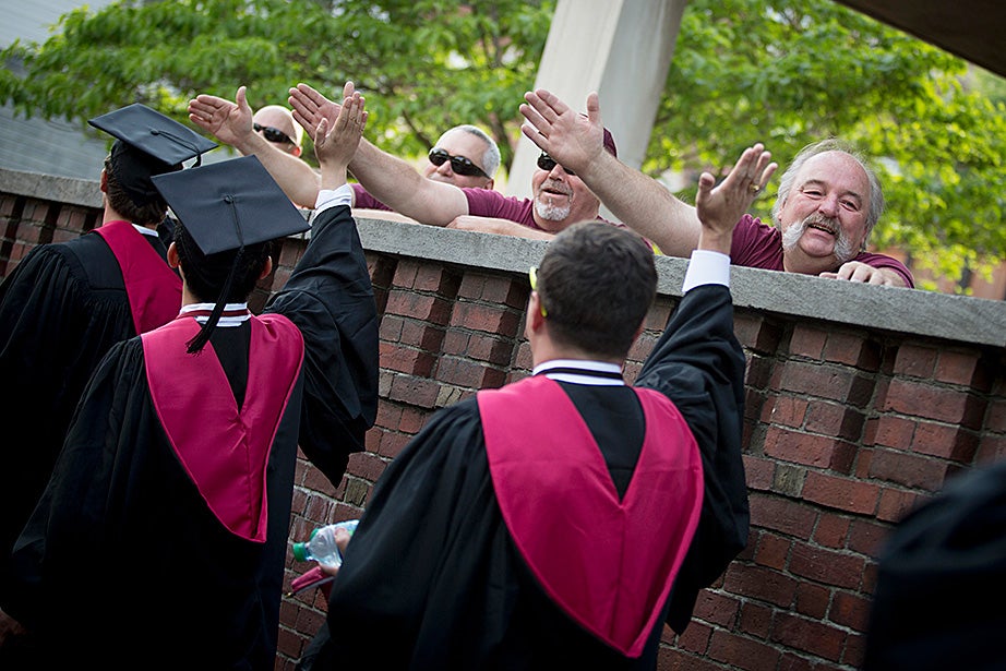 Custodians Bill Dyer (from right), Michael Shaw, Paul Hughes, and Tom Gallagher high-five graduates as they head into Tercentenary Theatre. Rose Lincoln/Harvard Staff Photographer