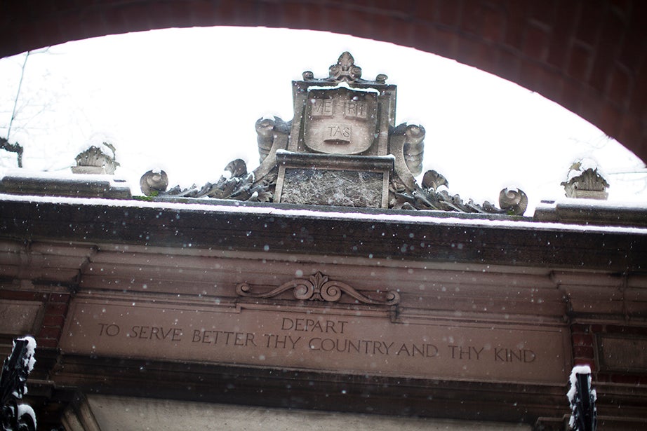 A Veritas shield on the inside of the 1890 (Dexter) Gate on Massachusetts Avenue, with an inscription below that reads, “Depart to serve better thy country and thy kind.” 