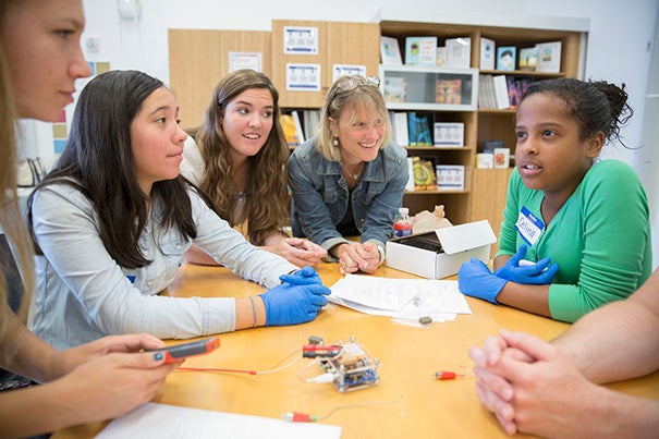 Katie Schmalkuche ’16 (from left),  eighth-grader Jade Diaz of Brighton; Emily Henson, program manager for HarvardX at Allston; Susan Johnson, Ed Portal manager of teaching and curriculum; and Braintree East Middle School sixth-grader Cynthia Henderson learn the basics of neuroscience at the Ed Portal in Allston.