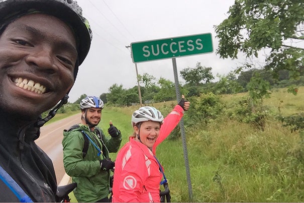 June 26: A road sign near Success, Mo., gives a team of Harvard and MIT students hope despite the distance still awaiting them in their 3,200-mile, coast-to-coast journey.  Harvard students Tola Omilana '16 (from left), Simon Shuham 
'17, and Francesca Childs '17 are part of a team called "Spokes," which taught STEM to schoolkids as they biked cross country. 