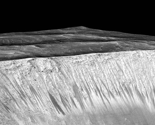 The dark streaks pictured are up to a few hundred yards, or meters, long. They are hypothesized to be formed by the flow of briny liquid water on Mars. 