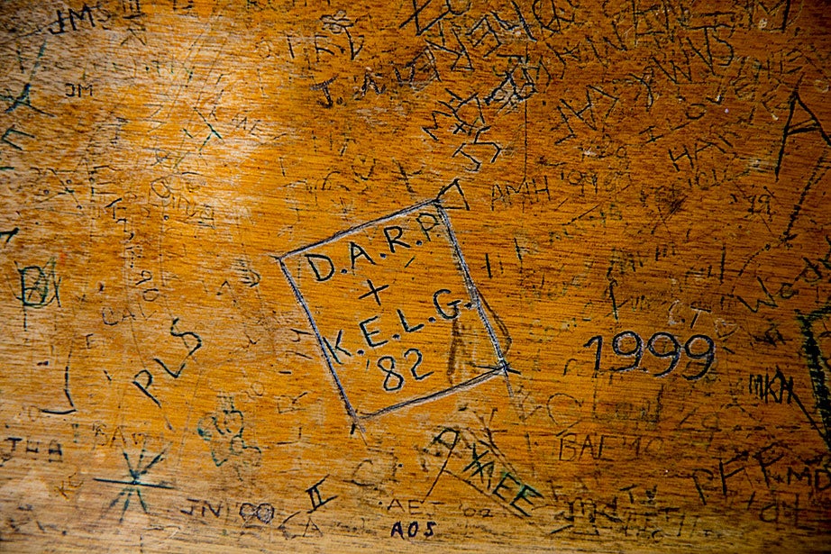 Years of student engravings cover a third floor oak table in the Hicks House library.