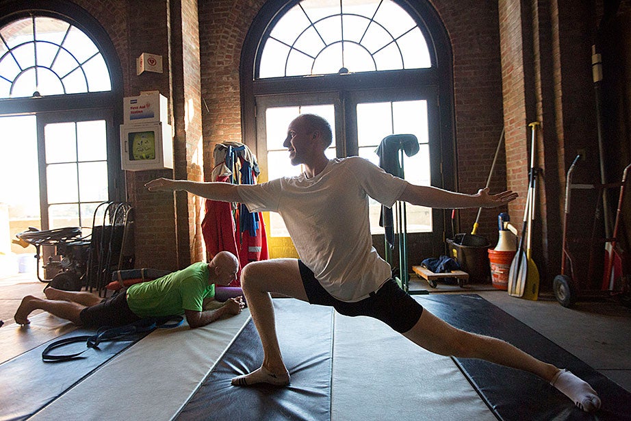 GSAS student Ben Oseroff stretches after training for the Head of the Charles. Mark Abelson, professor of ophthalmology at Harvard Medical School, planks in the background.