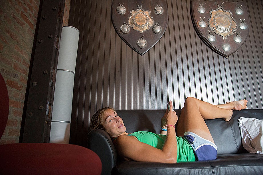 Princeton University rower Gevvie Stone, who is in training for the Olympics, rests in a team room beneath historical trophies.