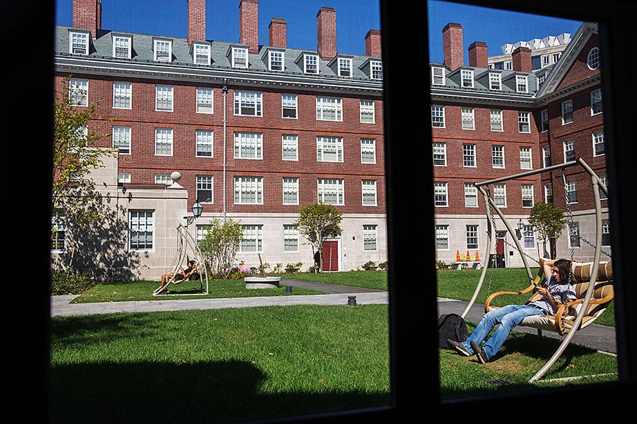 Students use social media on swinging chairs in the Dunster House courtyard. Kris Snibbe/Harvard Staff Photographer