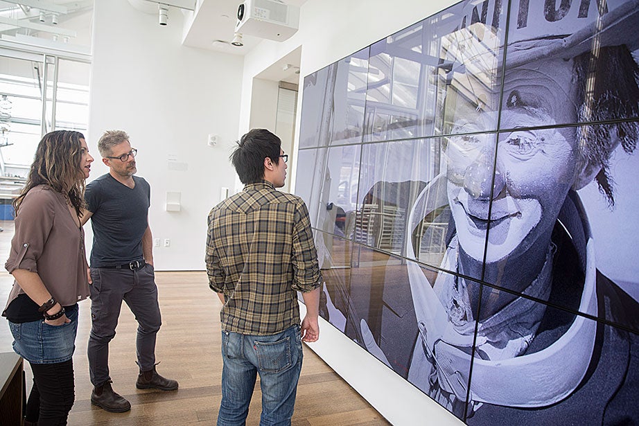 Sarah Newman (from left) and Matthew Battles work with technology fellow Ming Tu on “Your Story Has Touched My Heart.” The photo of the clown is a sample image used to test the screen. “The team’s projects infuse traditional modes of academic inquiry with an enterprising spirit of hacking, making, and creative research,” says Battles.