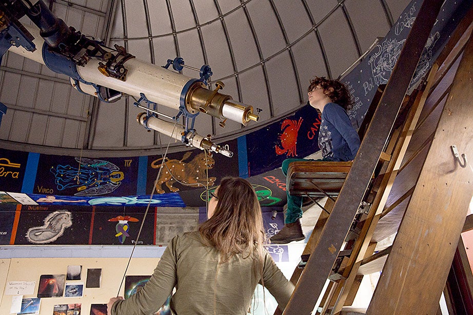 Michael Goldberg peers through the Loomis-Michael Telescope while Allyson Bieryla, manager of the Astronomy Lab and the Clay Telescope, helps him understand how it works.