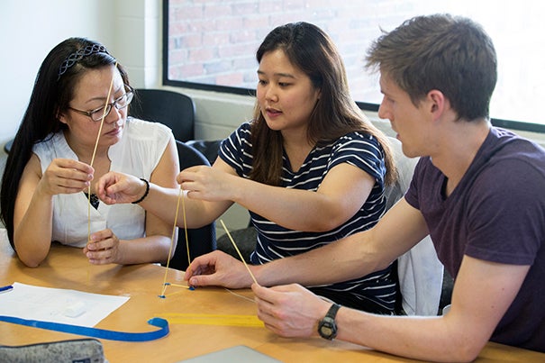 Irene Liu (left), Eunice Park, and Sam Fogel use spaghetti and tape to support a marshmallow during an exercise. Jon Chase/Harvard Staff Photographer