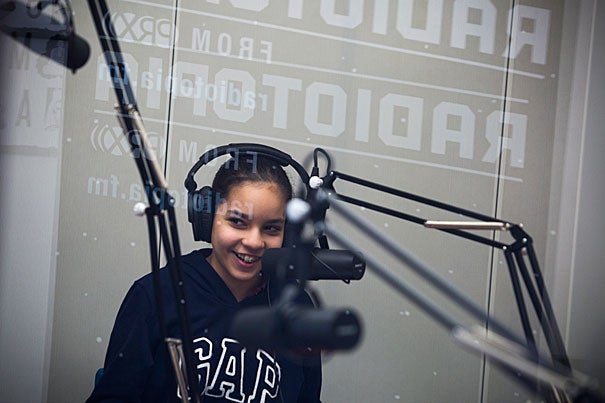 Gardner Pilot Academy sixth-grader Michelle Mota reads her story in the recording booth at the PRX Podcast Garage in Allston, where her class put together memoirs.