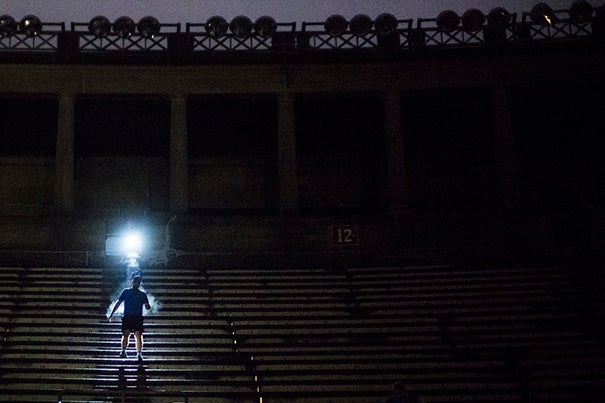 6 a.m. — A member of the 5:30 a.m. November Project group is illuminated by a fellow runner’s headlamp as he scales the stone steps of Harvard Stadium. He is one of hundreds of people who gather in the stadium every Wednesday morning, regardless of the month. Photo by Sarah Silbiger
