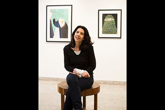 Artist Helen Zughaib is pictured in the exhibition space in CGIS South. Her pieces "Arab Spring Exodus" and "Arab Spring #2" are hung behind her. Stephanie Mitchell/Harvard Staff Photographer