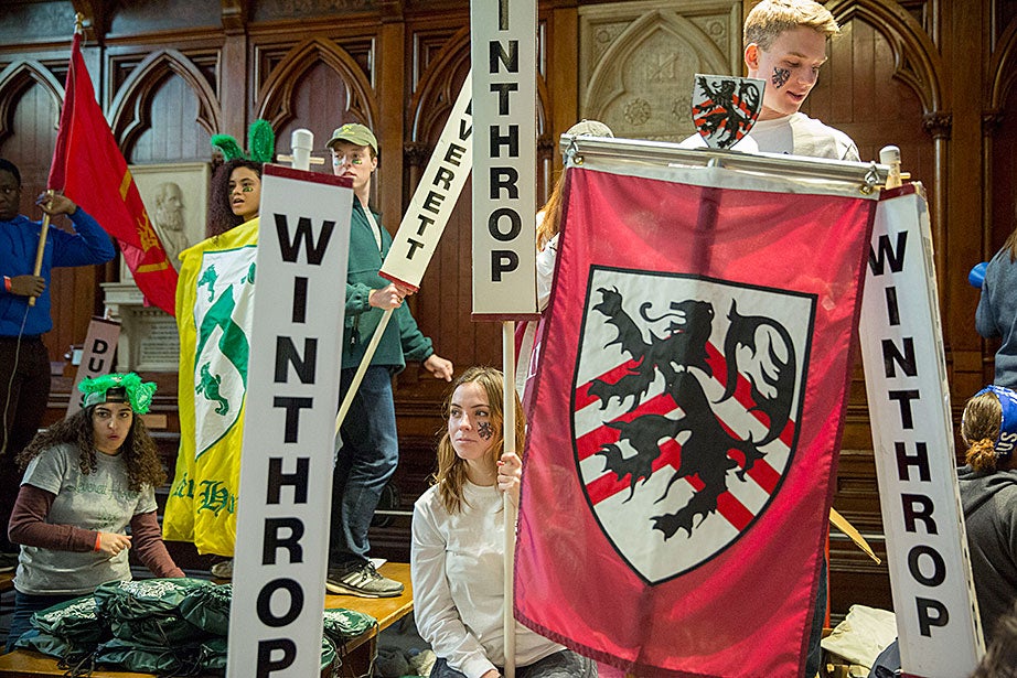 Isabel Wagner ’18 welcomes students to Pforzheimer House while celebrating Housing Day inside Annenberg Hall as Trevor Noon ’18 (upper right) holds a banner. Camille N’Diaye-Muller ’18 (far left) holds a Leverett House banner and wears bunny ears. Kris Snibbe/Harvard Staff Photographer