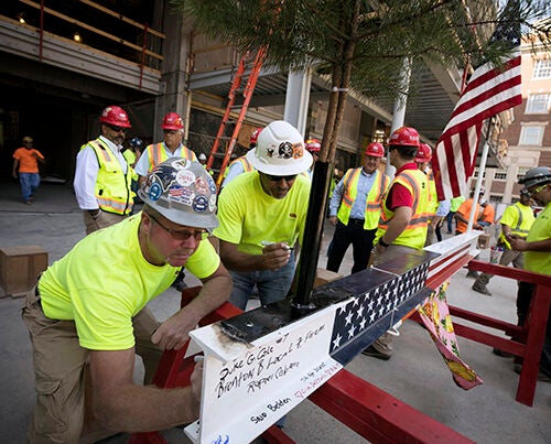Construction workers sign a beam during the topping-off ceremony at the Richard A. and Susan F. Smith Campus Center that marked the halfway point of the Center's renovations.
