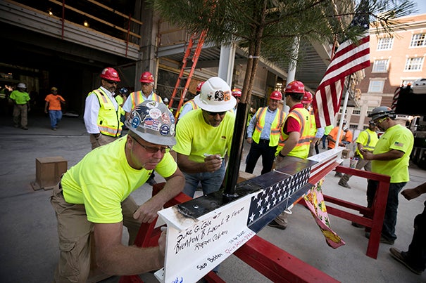 Construction workers sign a beam during the topping-off ceremony at the Richard A. and Susan F. Smith Campus Center that marked the halfway point of the Center's renovations.