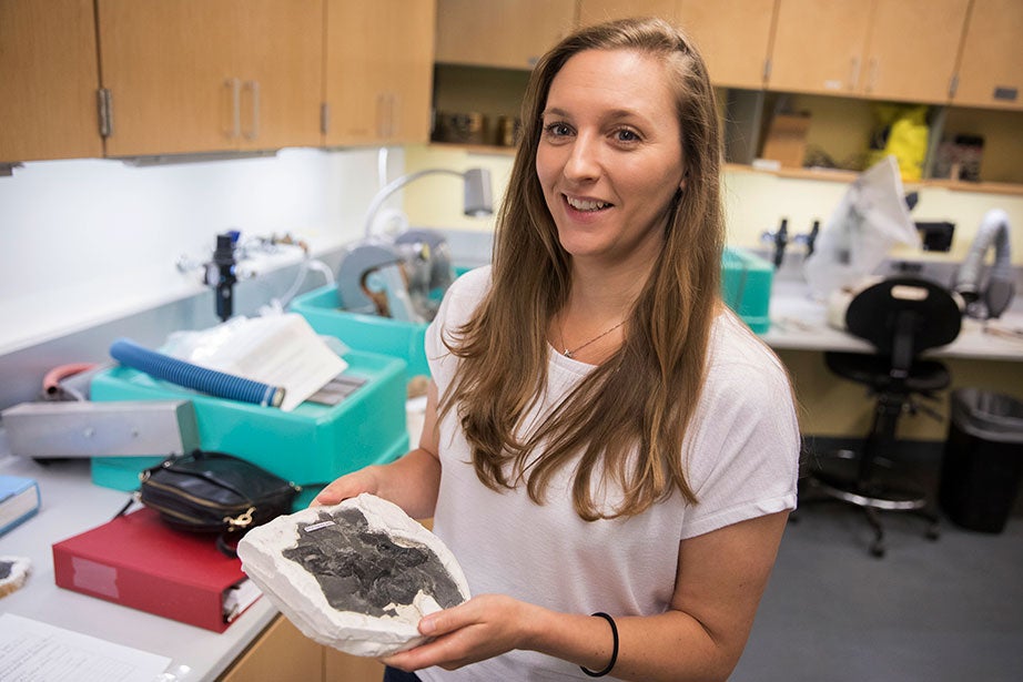 Stephanie Pierce, curator of vertebrate paleontology at Harvard’s Museum of Comparative Zoology, holds an early tetrapod fossil found in Nova Scotia.