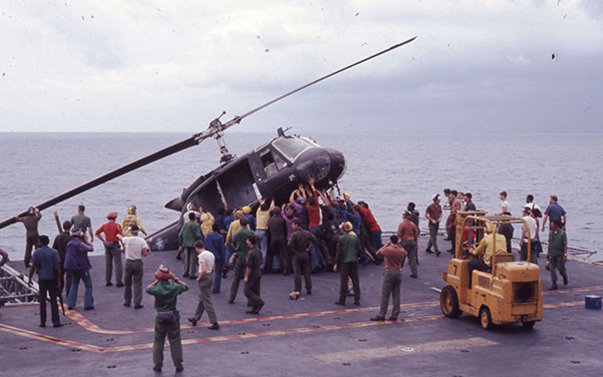 Crew members aboard the USS Okinawa push a South Vietnamese helicopter overboard to make room for incoming flights filled with evacuees Saigon fleeing the Vietcong.