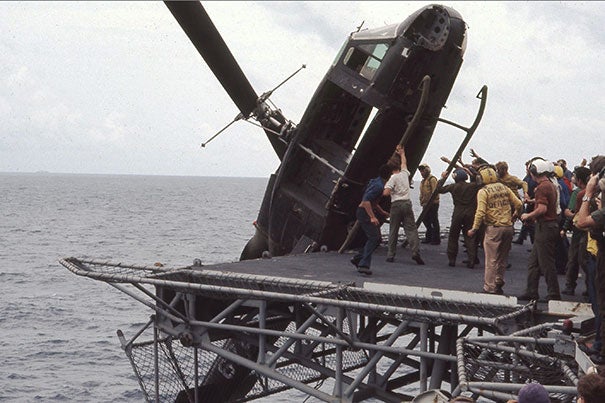 Crew members aboard the USS Okinawa push a South Vietnamese helicopter overboard to make room for incoming flights filled with evacuees Saigon fleeing the Vietcong.