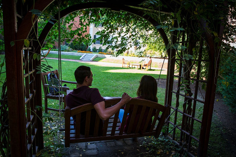 Grace Whitney '20 and Diego Covarrubias '20 talk under a wisteria-covered arbor on a swing in the courtyard.
