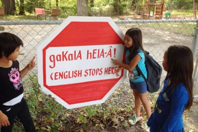 Outside the Yuchi House in Sapulpa, Oklahoma, a student sounds out the words on a stop sign informing students and visitors that English is not to be spoken on the premises. 