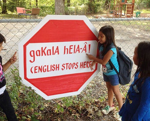 Outside the Yuchi House in Sapulpa, Oklahoma, a student sounds out the words on a stop sign informing students and visitors that English is not to be spoken on the premises. 