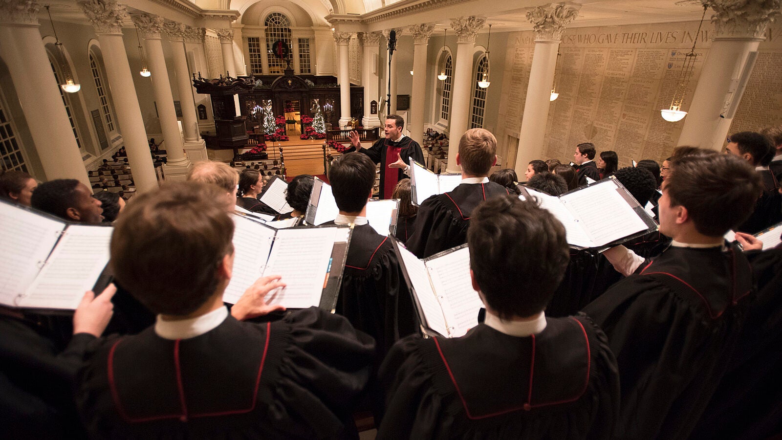 Choirmaster conducts Harvard choir during Christmas service in Memorial Church.