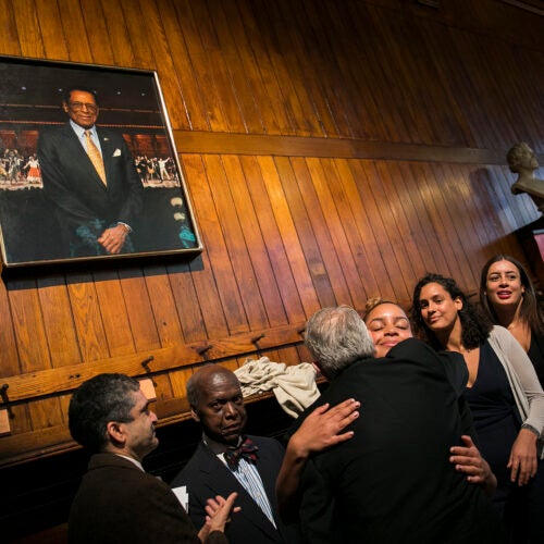 Rakesh Khurana (from left), David L. Evans, Portraiture Project Artist Stephen Coit '71, and daughters of S. Allen Counter Maya, Olivia, and Philippa embrace under the newly unveiled portrait of the late founder of the Harvard Foundation for Intercultural and Race Relations.