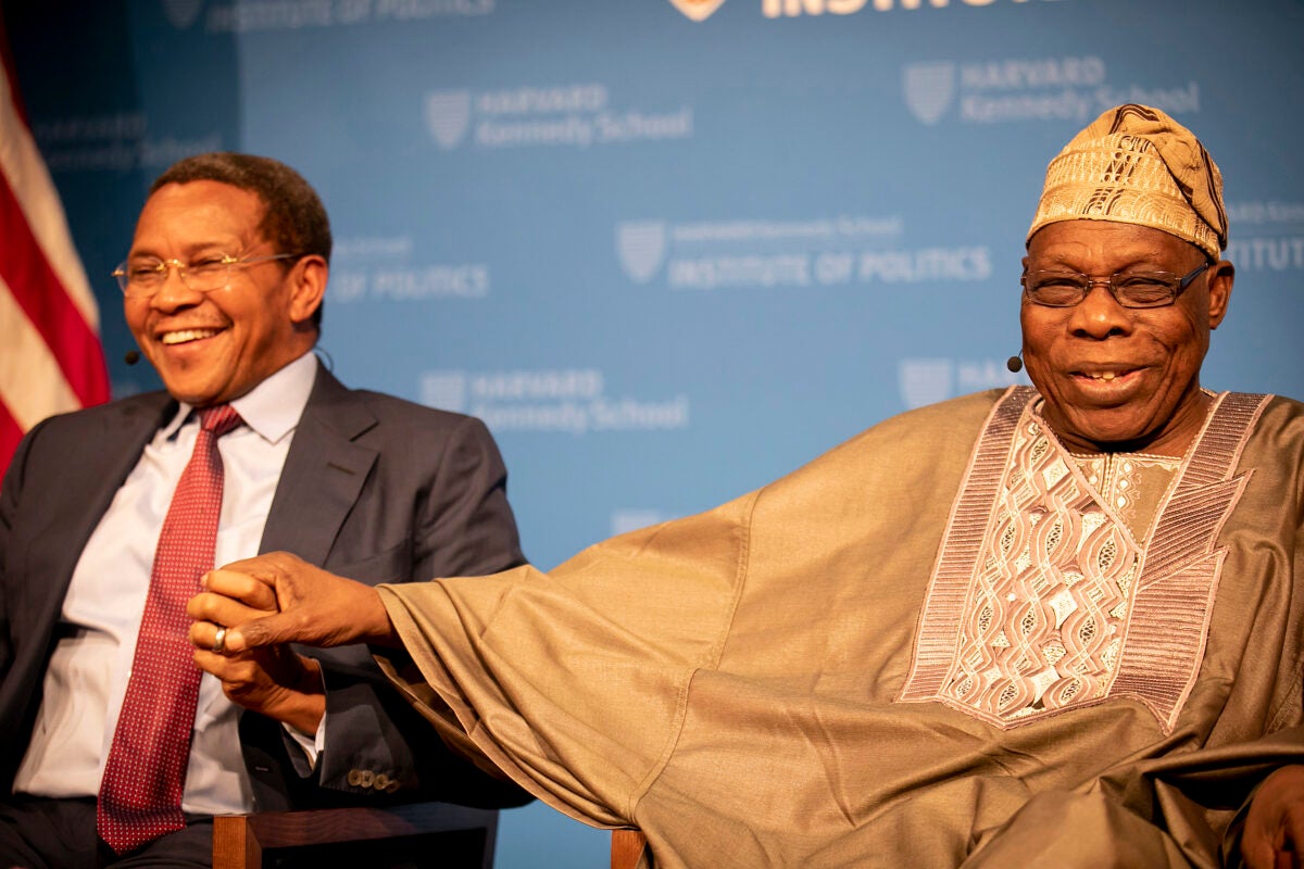 Former leaders Jakaya Mrisho Kikwet of Tanzania (left) and Olusegun Obasanjo of Nigeria take one another by the hand as they share a laugh during a Kennedy School panel on Africa's future.