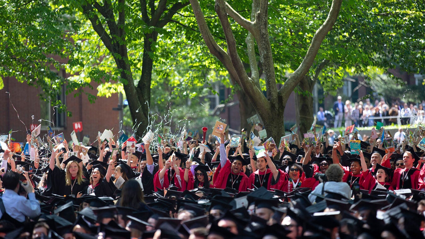 Harvard graduates wave books.