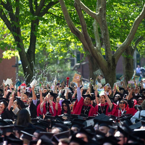 Harvard graduates wave books.