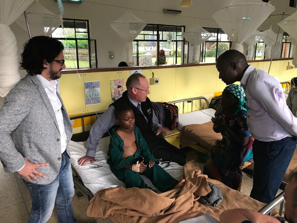 Paul Farmer and other doctors visit a 10-year-old Hodgkin Lymphoma patient in a hospital in Rwanda.