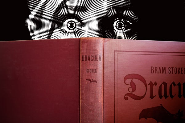 Illustration of frightened reader peering over "Dracula."