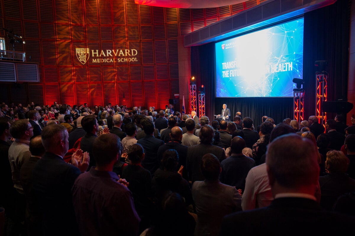 President Larry Bacow (at podium) described the Harvard Medical School gift from the Blavatnik Family Foundation as an “unprecedented act of generosity and support.” 