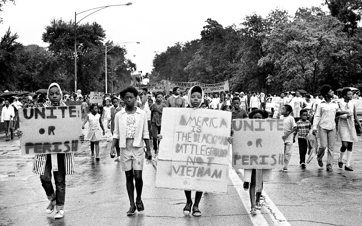 Vietnam War protesters march in Chicago in 1968 holding sign reading "Unite or perish."