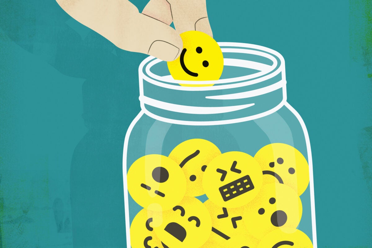 Hand choosing smiley face from jar of emoticons.