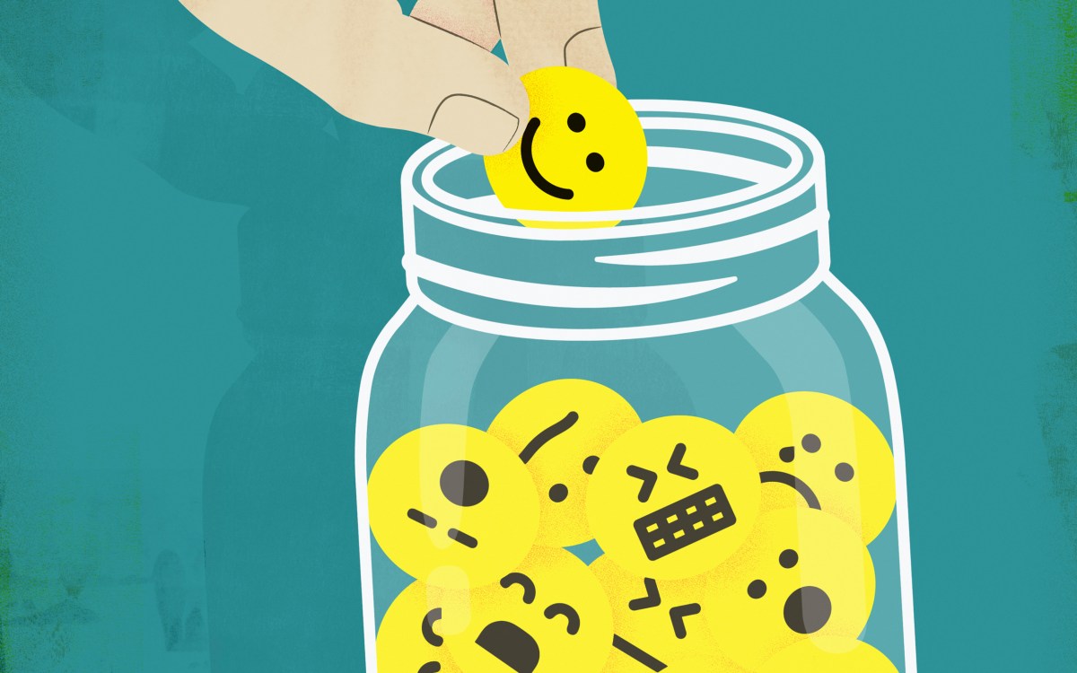 Hand choosing smiley face from jar of emoticons.